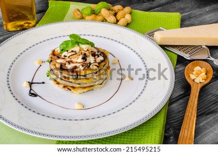 Grilled eggplant with feta cheese, parmesan, basil, nuts and balsamic reduction on wood plate