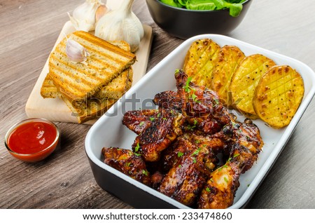 Sticky chicken wings with garlic bread panini, rustic spicy potatoes, fresh spinach leaves
