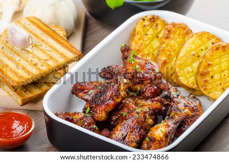 Sticky chicken wings with garlic bread panini, rustic spicy potatoes, fresh spinach leaves