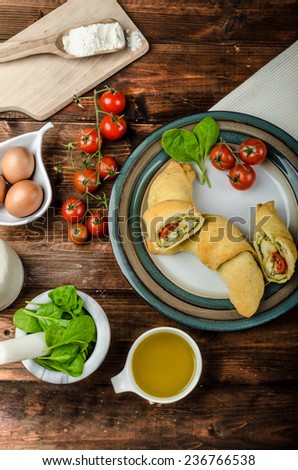 Home calzone rolls stuffed with cherry tomatoes, basil pesto and spinach with bio garlic