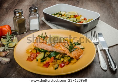 Salmon baked with thyme and Mediterranean vegetables on wood table with plate