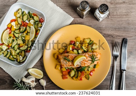 Salmon baked with thyme and Mediterranean vegetables on wood table with plate