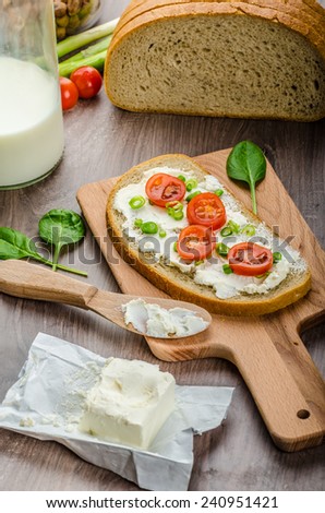 Fresh bread smeared with cream cheese, cherry tomatoes and spring onions, milk from farm