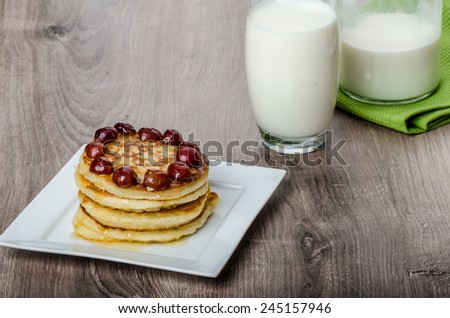 Home fluffy pancakes with cherry cherries and honey, milk drink