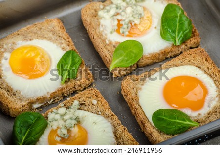 Baked Bull\'s-Eye Eggs on whole wheat toast with spinach and blue cheese on top