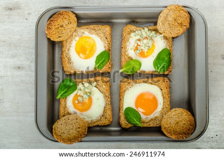 Baked Bull\'s-Eye Eggs on whole wheat toast with spinach and blue cheese on top