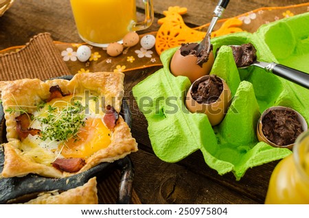 Fried eggs in puff pastry in ham, baked with cheese and topped with microgreens, fresh juice from oranges and eggs stuffed with chocolate