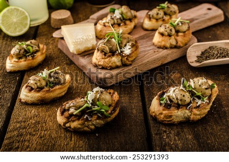 Mushroom snacks on grilled baguette, topped with parmesan cheese and microgreens, fresh lime juice