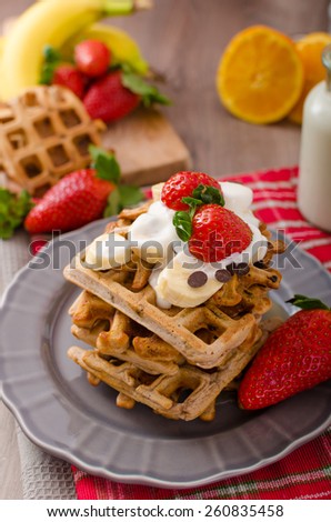 Belgian waffles with chocolate, bananas and strawberries, syrup-drenched