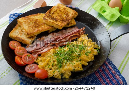 Scrambled eggs with bacon and French toast on a cast iron pan