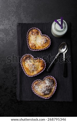 Valentine\'s Day mini heart-shaped tart with lemon and creame, clean black composition, milk and spoons