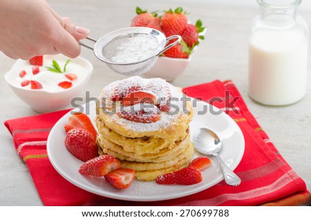 Fluffy pancakes with strawberries, sprinkled with sugar, with healthy milk and creamy dip
