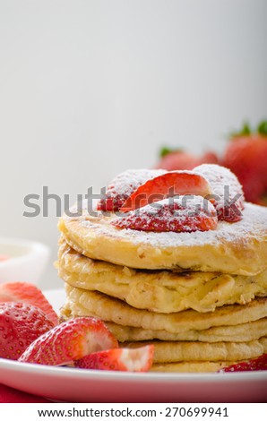 Fluffy pancakes with strawberries, sprinkled with sugar, with healthy milk and creamy dip