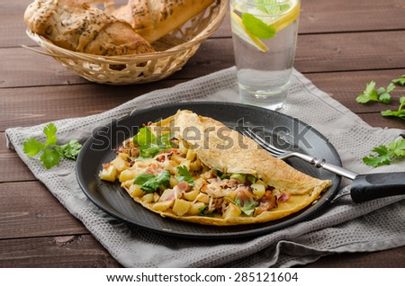 Country egg omelette filled bacon, parsley and potatoes, sprinkled with cheese and herbs