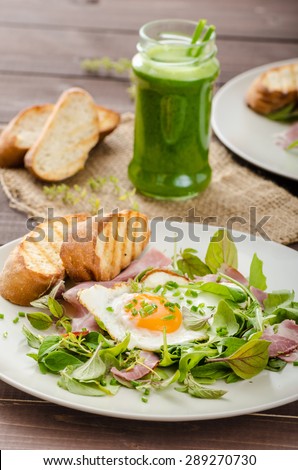 Light summer salad with a fried egg and nuts, herbs and avocado smoothie with spinach, toast panini