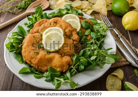 German schnitzel with homemade fries, lemons and limes, tomatoes and lamb\'s lettuce salad