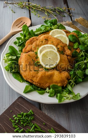 German schnitzel with homemade fries, lemons and limes, tomatoes and lamb\'s lettuce salad