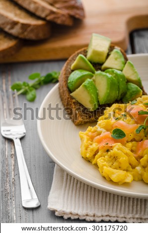 Scrambled eggs with smoked salmon and whole wheat toast with avocado and lemon