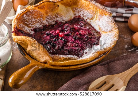 Dutch baby pancake with berries, delicious pancake baked in oven on iron skillet