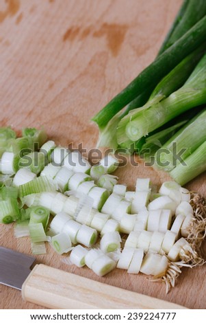 chopped green spring onions on wooden cutting board