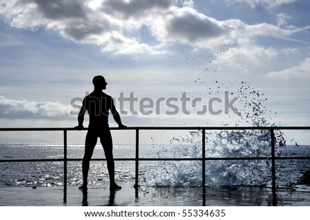 Silhouette of young man standing at the seaside -wave splash