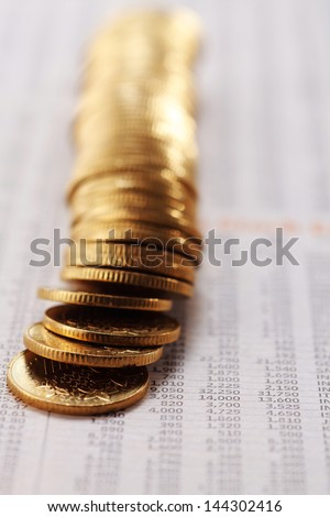 Stack of coins on list of share prices