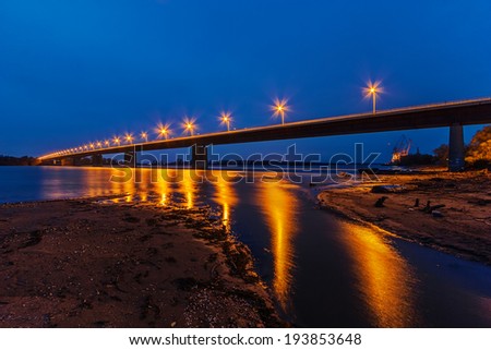 Steel bridge across river at night with artificial lightning