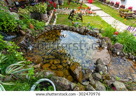 Fountain with grass and flowers in backyard of an old Serbian mountain house