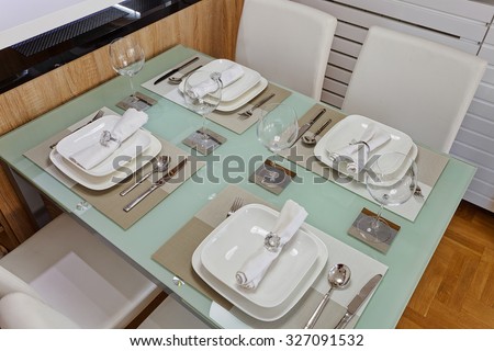 Contemporary dining area with glass top dining table and four white leather chairs