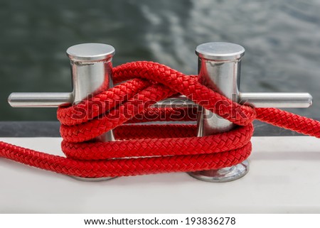 Red rope fasten on stake of yacht