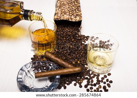 A bottle of whiskey and a glass with a Cuban cigar and coffee beans