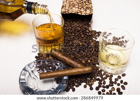 A bottle of whiskey and a glass with a Cuban cigar and coffee beans