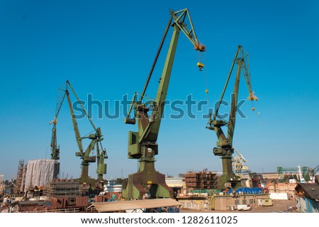 Sunny morning with historical port cranes in the industrial part of the city Gdansk (Gdańsk) in Poland (Polska). Work in progress. Industrial view of shipyard known all over the world.