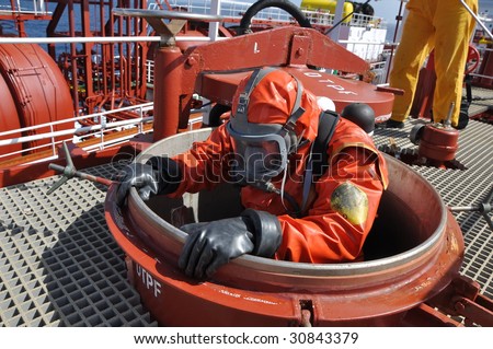 man in chemical suit entering inside  cargo tank on chemical ship for cleaning operation