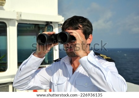 navigator on navigation bridge during his watch on seagoing vessel with binocular