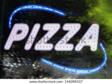 A blue and white illuminated sign that reads Pizza