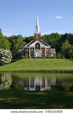 A beautiful church on a hillside overlooking a pond