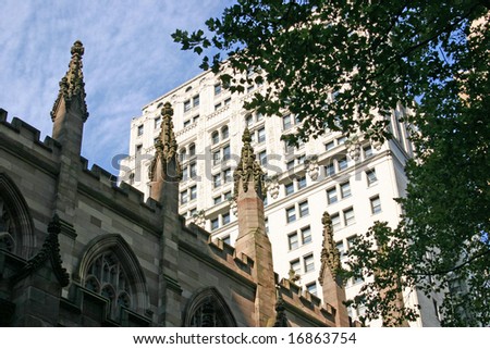 The spires of Trinity church set again a modern building in New York City