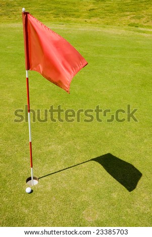 Red flag on a golf course and ball close to a hole