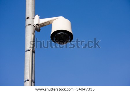 Security camera located on a post over a street