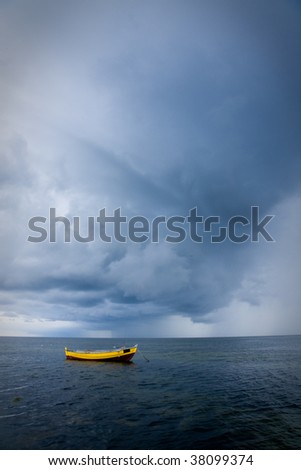 Yellow fishing boat in a sea against dramatic dark sky during storm