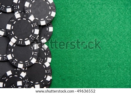 Black gambling chips on green felt background with copy space