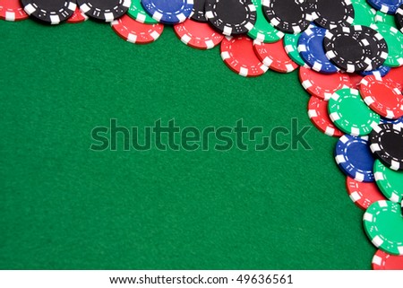 Colorful gambling chips on green felt background with copy space