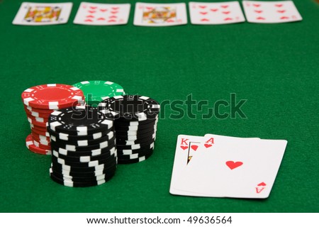 Royal flush of hearts on poker table and gambling chips on green felt