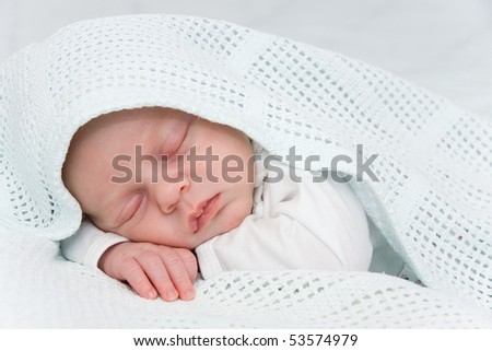 Newborn boy covered by blue blanket sleeping