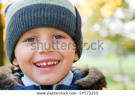 Three years old boy in cap smiling in autumn scenery