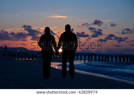 Silhouette of couple taking a walk on beach in sunset