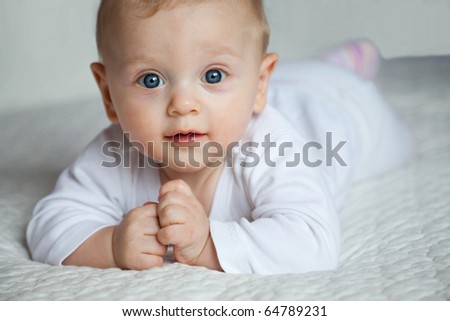 Smiling newborn boy in bright clothes lying on bed