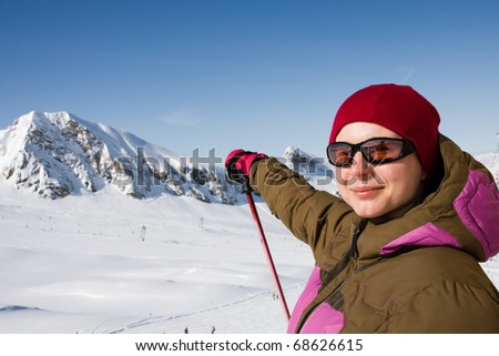 Woman in ski clothes pointing hill in alps mountains