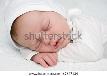 Two weeks old newborn boy in cap sleeping